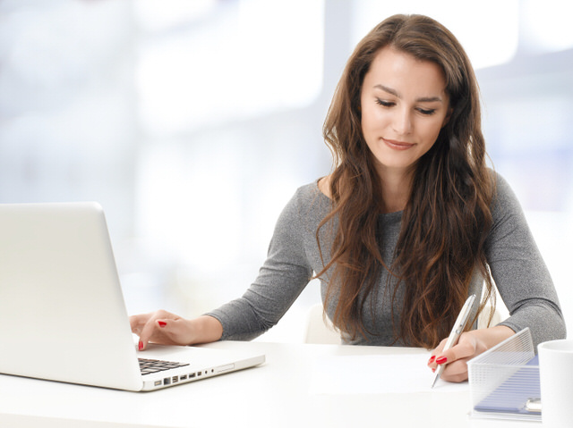 Portrait of sales woman analyzing datas on computer while sitting at office.